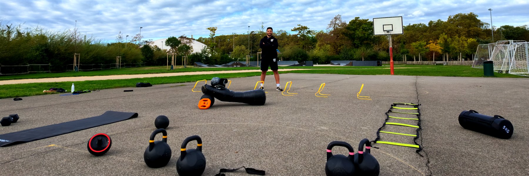 Sami, coach System HIIT, avec le matériel des cours en plein air à Morges : kettlebells, échelle d’agilité, haies et sac bulgare